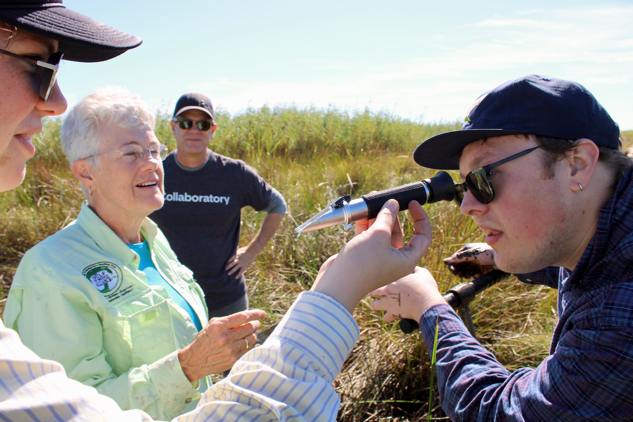 man looking through microscope in marsh land