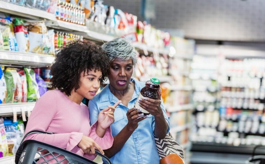 Two women in a supermarket read a food label.