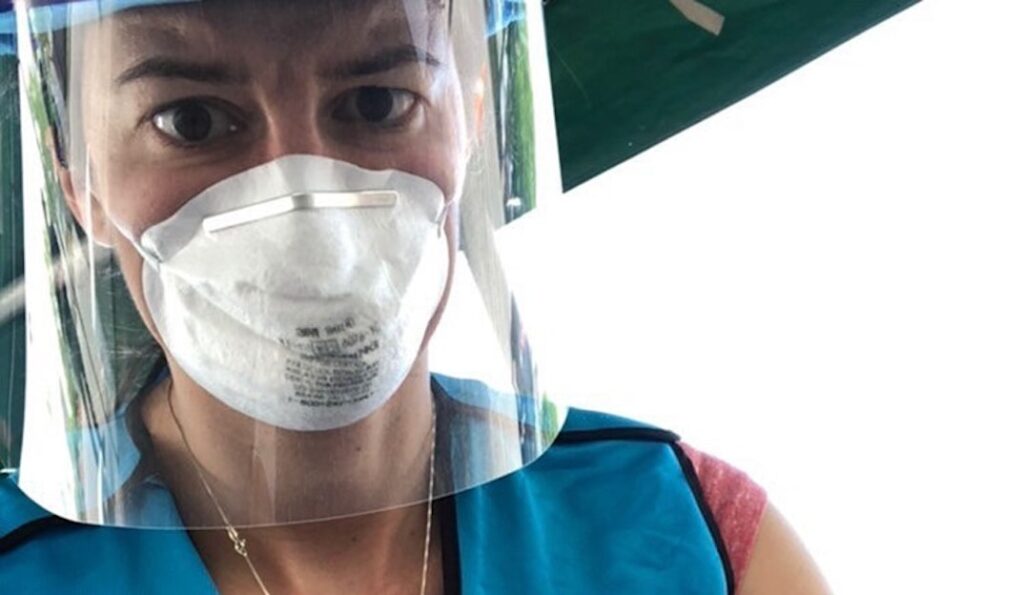 Tulane faculty member Dr. Julie Hernandez wearing a protective face mask and plastic face shield while volunteering with a mobile response team.