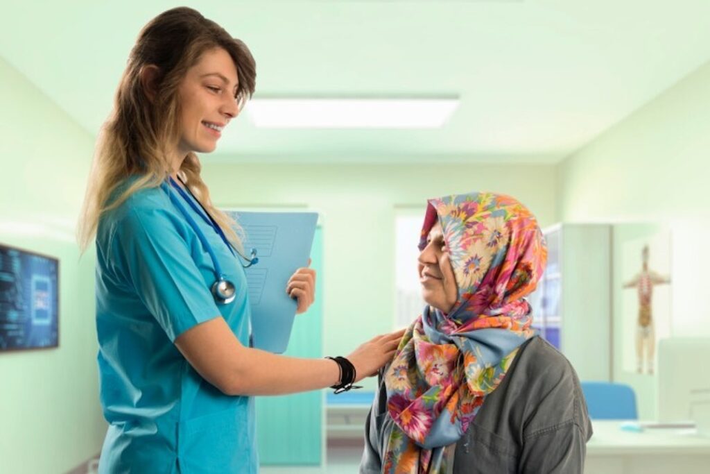 A nurse talks with a patient in a headscarf.