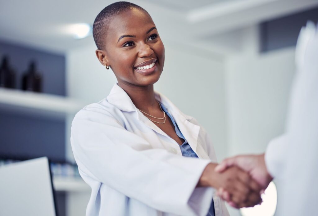 Healthcare manager shaking hands with another healthcare professional in an office