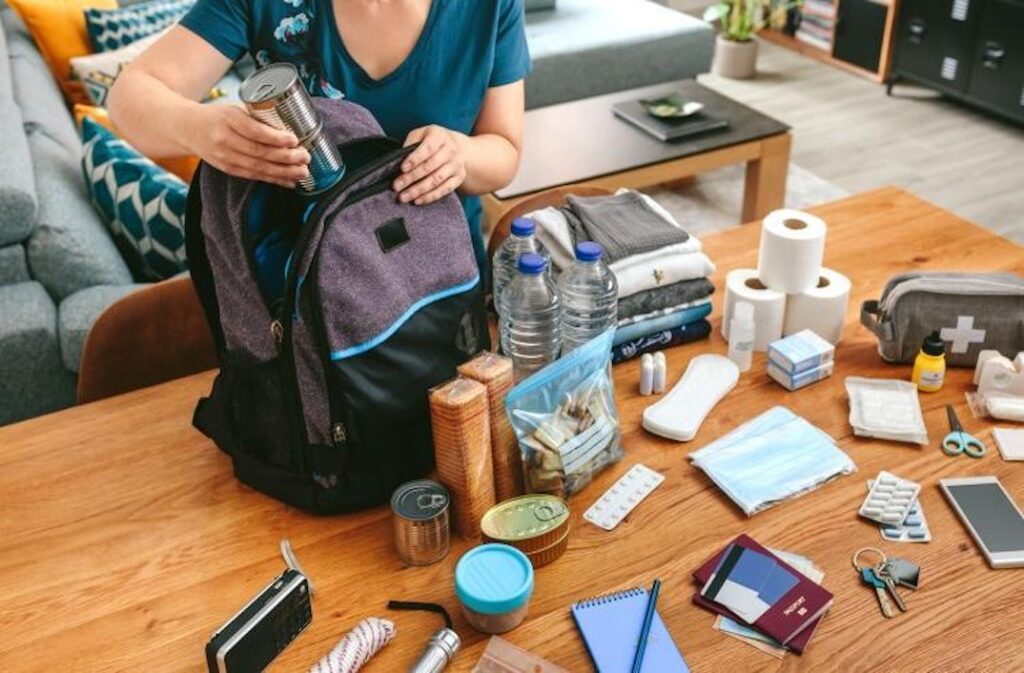 Person preparing an emergency backpack for a potential disaster.