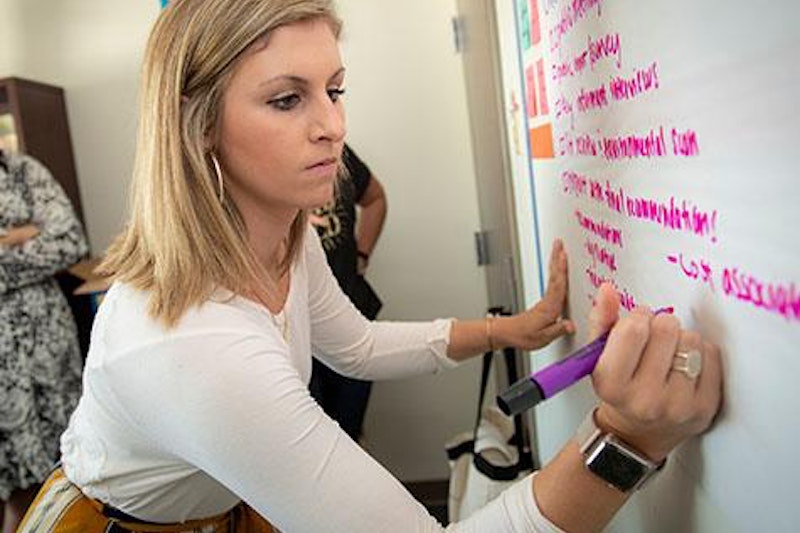 A woman writing at a whiteboard