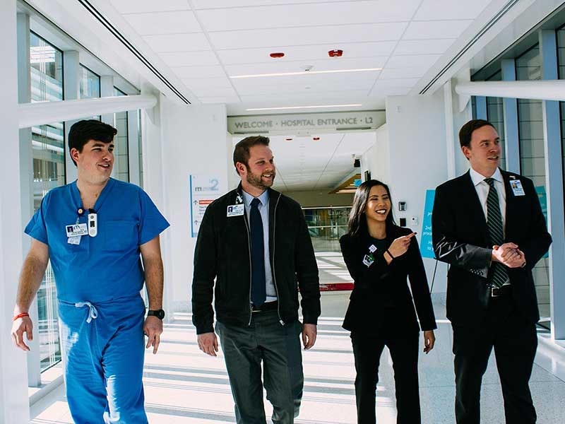 A group of health and management professionals walk down the hallway of a hospital