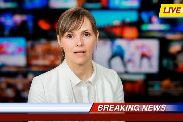 A TV newscaster reports live breaking news as part of a disaster communication plan.
