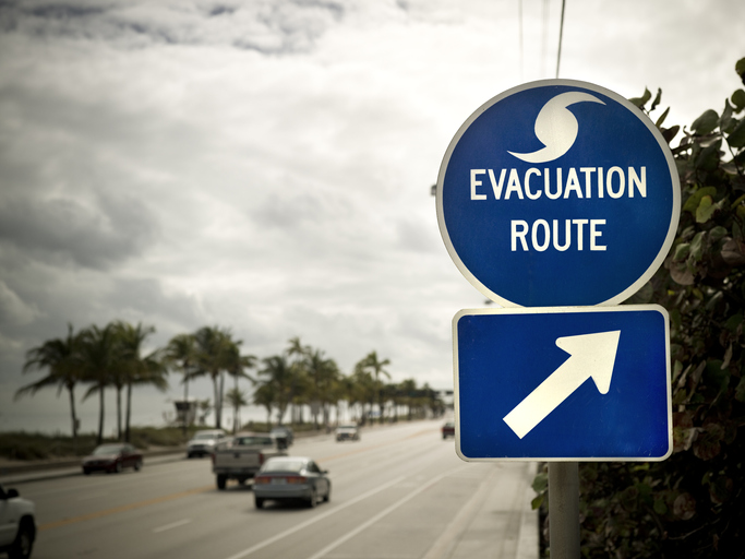 Cars pass by a hurricane evacuation route marker.