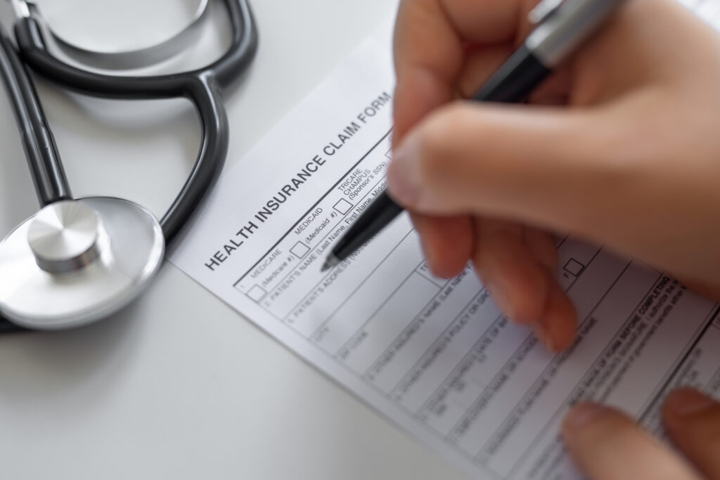 A healthcare worker filling in a health insurance claim form.