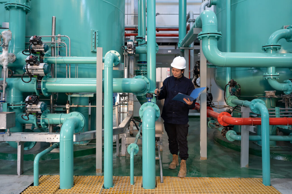 An industrial hygiene professional examines a pipe in a plant.